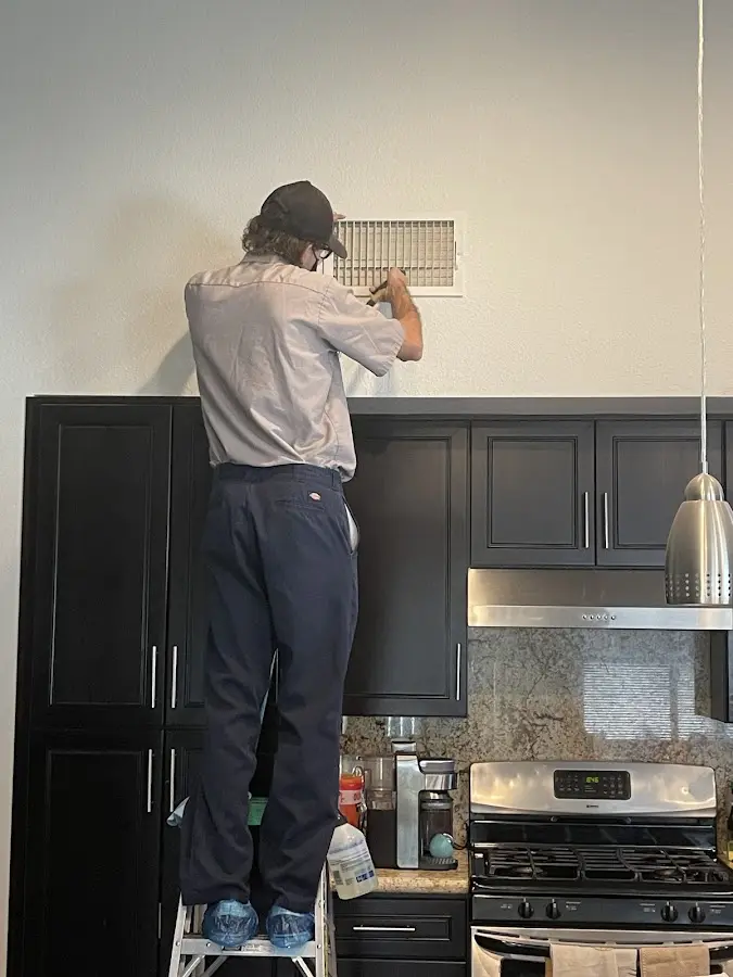 Technician inspecting an air vent during HVAC service in Cambria